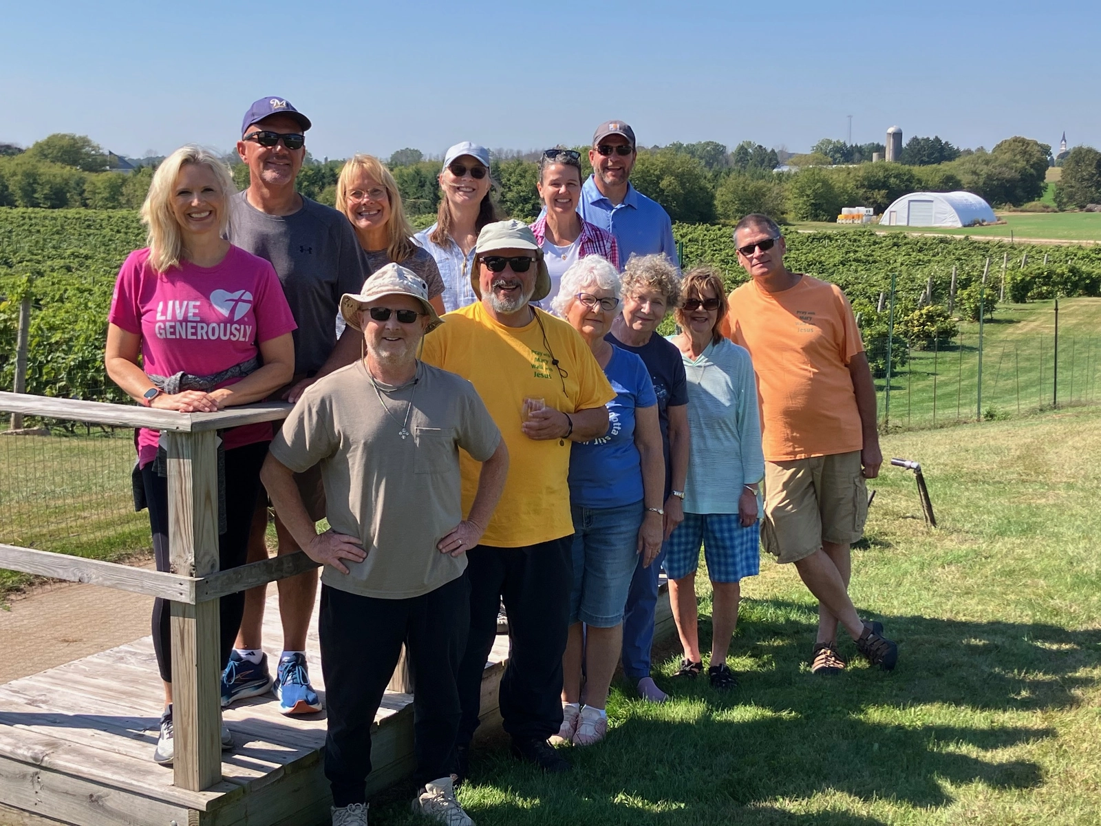 A large group of pilgrims posing together beside a vineyard