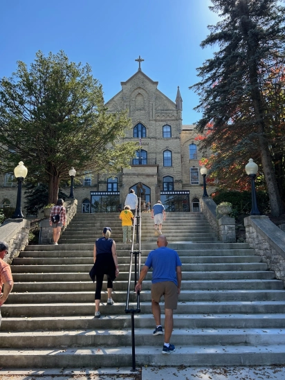 Pilgrims climbing a long flight of stone steps toward a large stone church