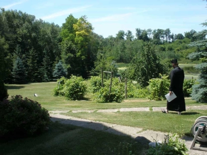 A monk in a black habit walking across a green lawn
