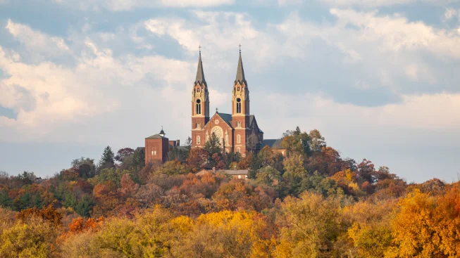 The twin spires of Holy Hill basilica rising above autumn trees